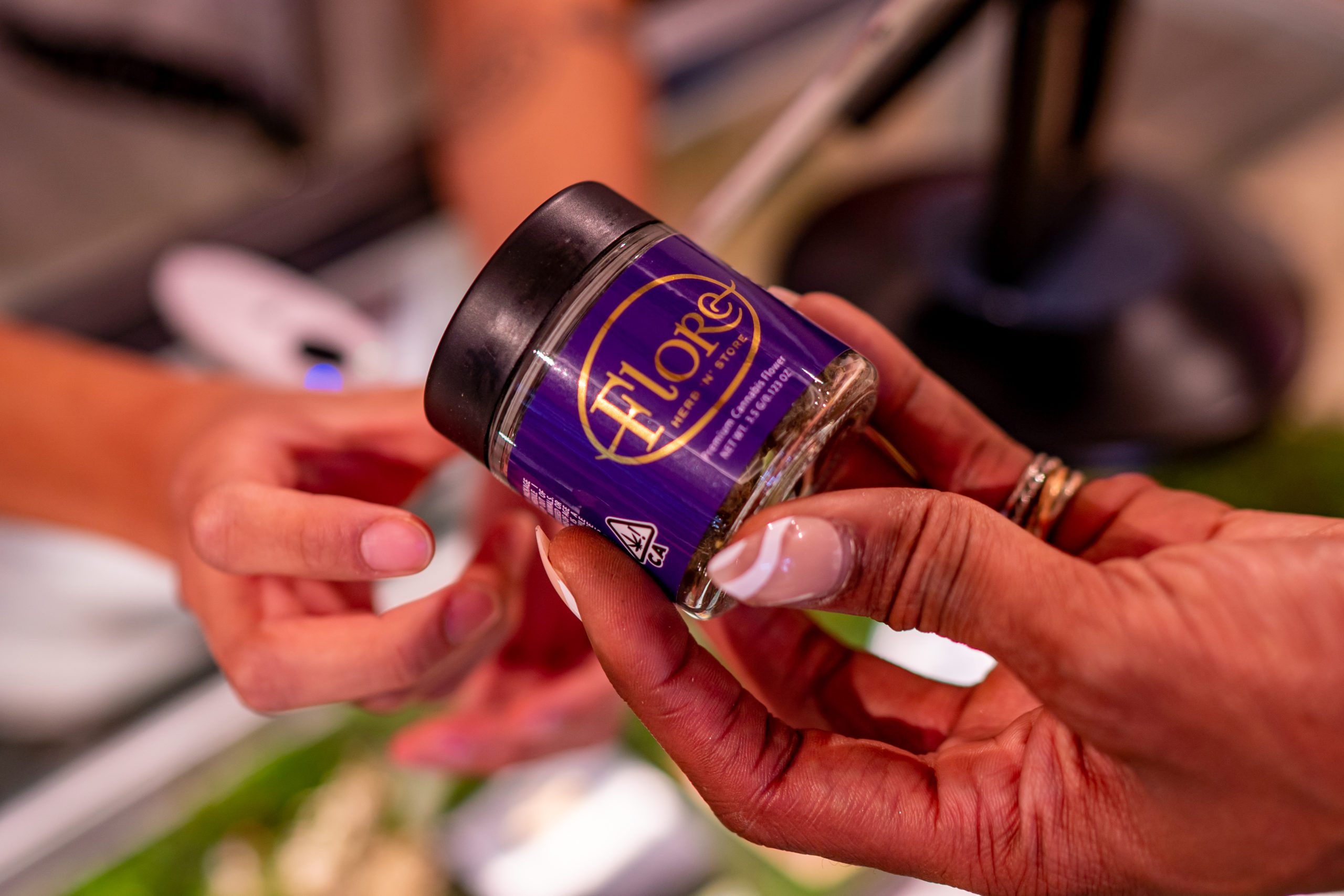 Customer receiving jar of Flore cannabis flower at checkout counter.