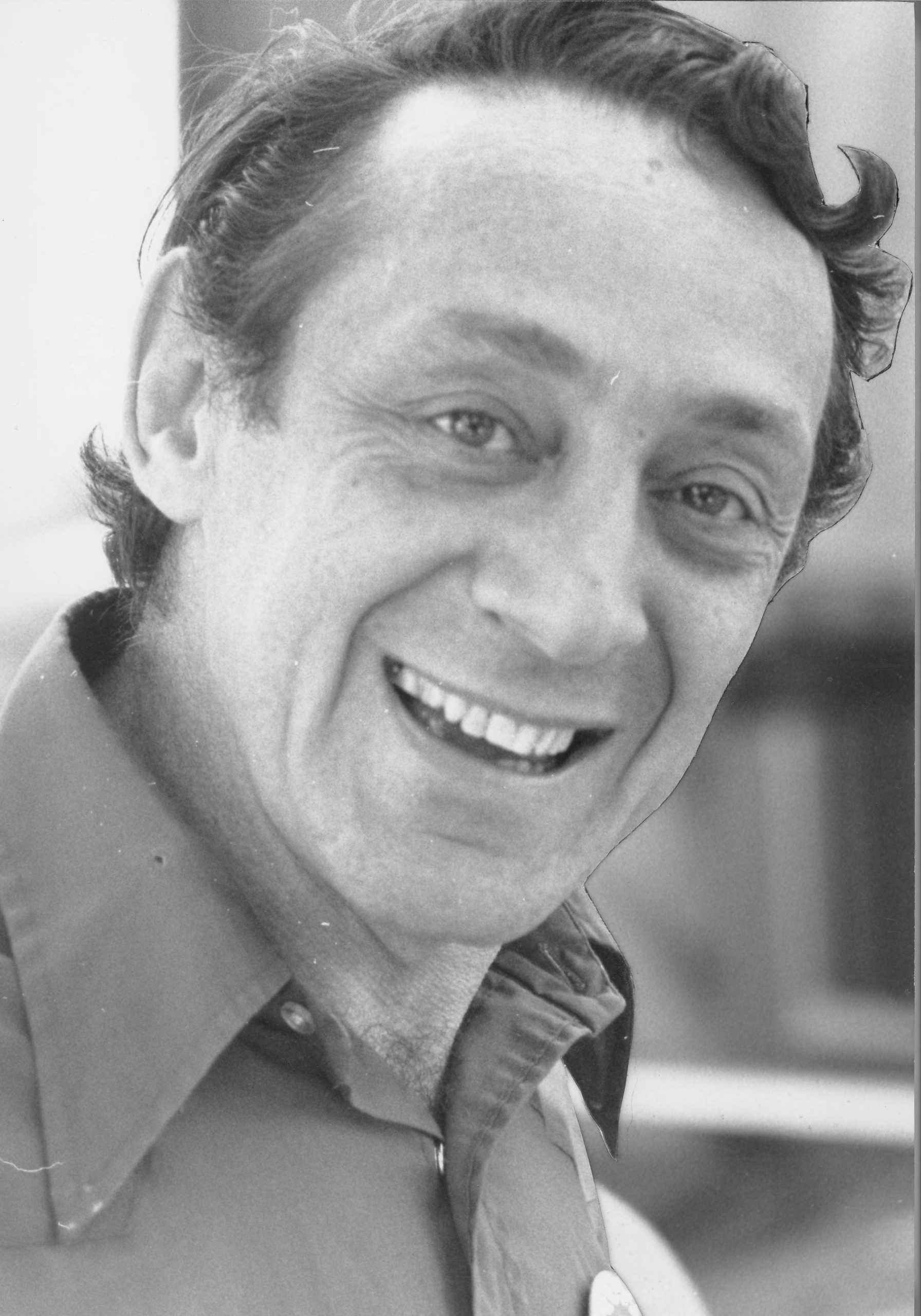 Smiling man in black and white portrait wearing collared shirt.